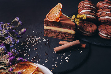 Baking background with chocolate cake, a cup of coffee, biscuits, dried citrus, on dark  background. Flat lay with copy space. view from above.