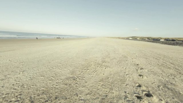 Fast aerial shot of a beach in Domburg with people surfing.