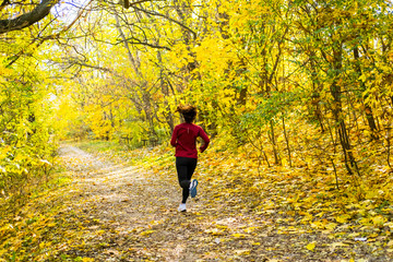 Obraz premium Young happy woman runner training in sunny autumn park