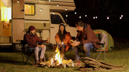 Group of close friends laughing together around camp fire