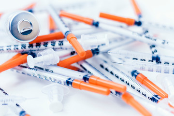 Pile of medical syringes for insulin for diabetes on white table.