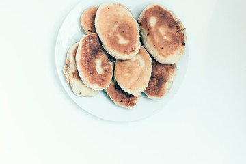 Traditional homemade fried patties or pies made of yeast dough in a rustic style on white plate.