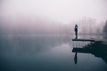 Man standing on a deck above a misty lake. Depression and suicide concept. - Powered by Adobe