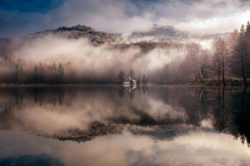 Fototapeta premium Foggy day at a lake with a little island with a church in the middle. Mogoasa, Romania.