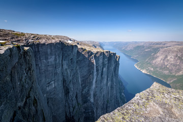 Girl hiker laying on belly to look into the ravine at Lysefjord Norway