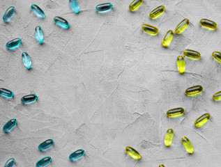 Fototapeta na wymiar yellow and blue vitamin capsules on gray background with copy space, soft gelatin capsule with oily drug. The concept of pharmacology, homeopathy and medicine