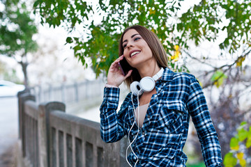 Beautiful young woman is listening music in the city