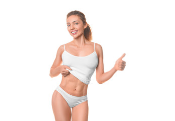 Obraz premium Smiling woman showing her waist and keeps thumb up. Isolated on white.