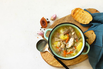 Homemade hot vegetable soup with chicken, mushrooms and bulgur on a white countertop. Top view flat lay background. Copy space.