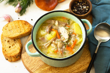 Homemade hot vegetable soup with turkey, mushrooms and bulgur on a white countertop.