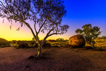 Australian outback landscape of Devils Marbles rock formations after twilight. Bush vegetation of...
