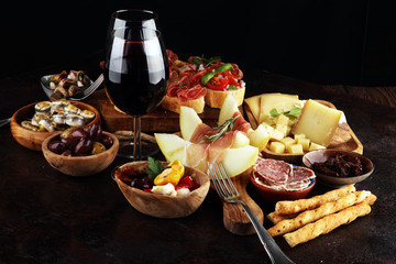 Italian antipasti wine snacks set. Cheese variety, Mediterranean olives, seafood salad, Prosciutto di Parma, tomatoes, anchovy and wine in glasses