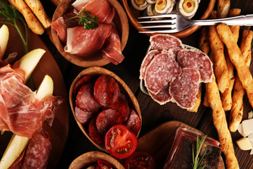 Italian antipasti wine snacks set. Cheese variety, Mediterranean olives, seafood salad, Prosciutto di Parma, tomatoes, anchovy and wine in glasses