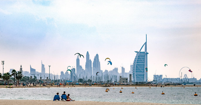 Holiday beach scene from Dubai with kites and high rises in the background.