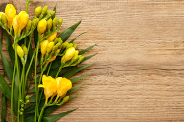 Yellow freesia flower on wooden background - obrazy, fototapety, plakaty