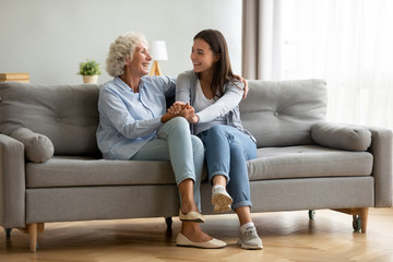 Happy adult granddaughter and senior grandmother having fun enjoying talk