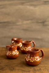 Mini traditional mexican clay cups on a wooden surface against a rocky background