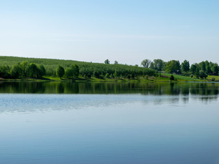 beautiful summer landscape with lake and green trees on shore.  calm water and reflections