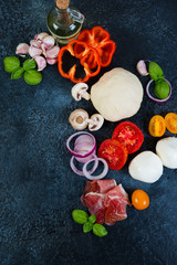 Fototapeta na wymiar The ingredients for making pizza lie on a black concrete background. Vertical orientation. Top view