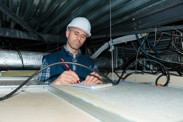 electrician making notes in roof space