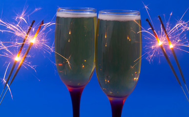 Two glasses of sparkling wine and burning sparklers 