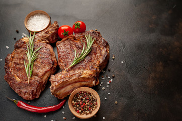 two grilled beef steaks with spices on a stone background with copy space