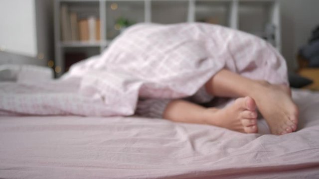Closeup view of feet lying on soft white pillow at bed