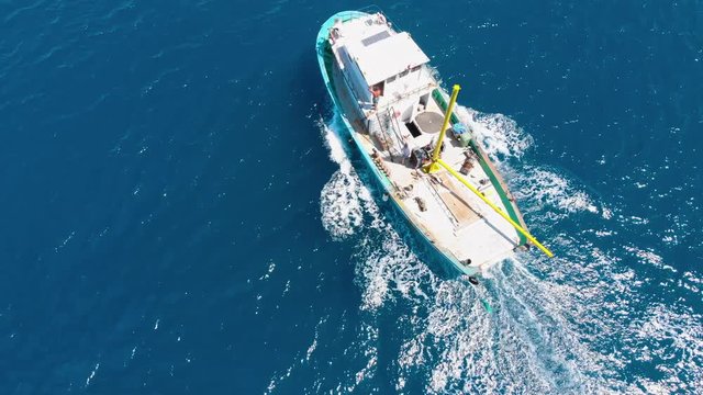 A small fishing boat in the afternoon goes at full speed into the open sea to search and catch salmon against the backdrop of the mountain. Fishing in the ocean, shooting from a helicopter.