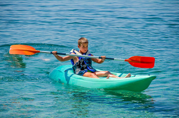 kayaking lessons. Boy with  life buoy suit in kayak lessons during summer vacations in an island of Greece.