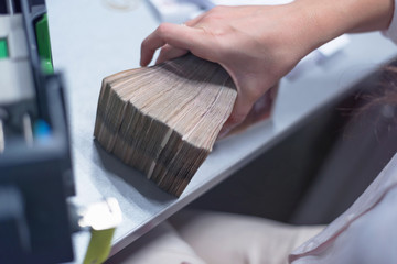 Finance person organizing large number of banknotes at the center for cash services.