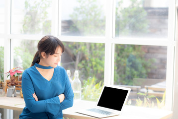 Beautiful of portrait asian young woman sitting looking camera and laptop on desk at coffee shop, professional female freelance working notebook computer connect internet online job, business concept.