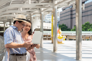 Couple Using Laptop While Standing On Bridge In City