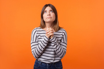 Portrait of faithful young woman with brown hair in long sleeve shirt standing, looking up and...