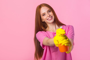 beautiful young woman with red hair in yellow rubber gloves on a pink background