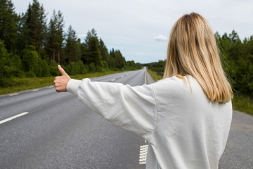 Woman with blond hair an empty road. Girl waiting. Search for a new way. Hitchhiking trip. Travel, adventure. Sense of freedom, enjoy relax lifestyle. Scenic view, landscape. Explore North Norway