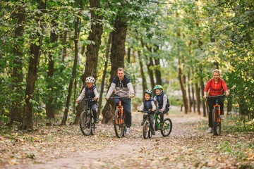 Foto op Plexiglas parents and kids cycling on forest trail. Young family in warm clothes cycling in autumn park. Family mountain biking on forest. Theme family active sports outdoor recreation. © Elizaveta