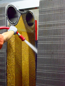 Technical worker cleaning Heat exchanger plate of the water cooling system on power plant.