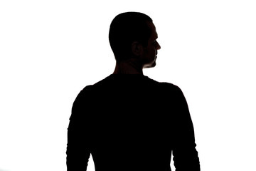 Silhouette of adult man standing back to camera in studio