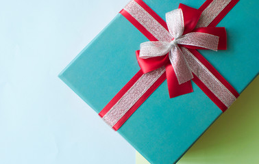 single christmas gift box with ribbon and bow on a paper of different colors