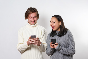 Happy friends laughing and watching a smart phone on white background