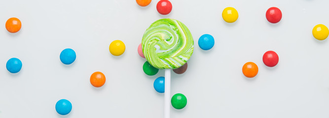 Lollipop on a stick, on a white table and colorful dragees