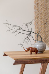 Close up of design wooden table with stylish sculpture, flowers in vase and elegant accessoreis....