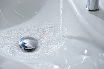 Water flows into a new white sink in the bathroom