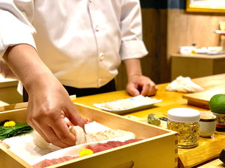 Obraz na płótnie Canvas Closeup of chef hands preparing japanese food. Japanese Omakase Chef making sushi at restaurant. chef serving traditional japanese sushi with gold served on a stone plate.