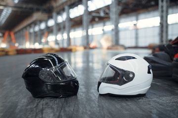 Two go kart helmets on the ground, karting