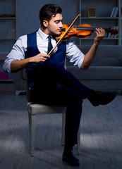 Young musician man practicing playing violin at home