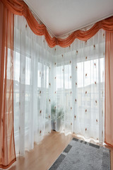 Beautiful corner window to the floor with a curtain