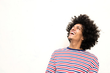 happy young man with afro hair laughing and looking yup against white background