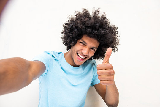 happy young North African man taking selfie against white background with thumbs up hand sign