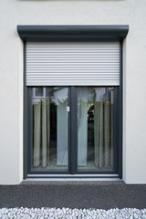 Light roller shutter curtains mounted on a dark window